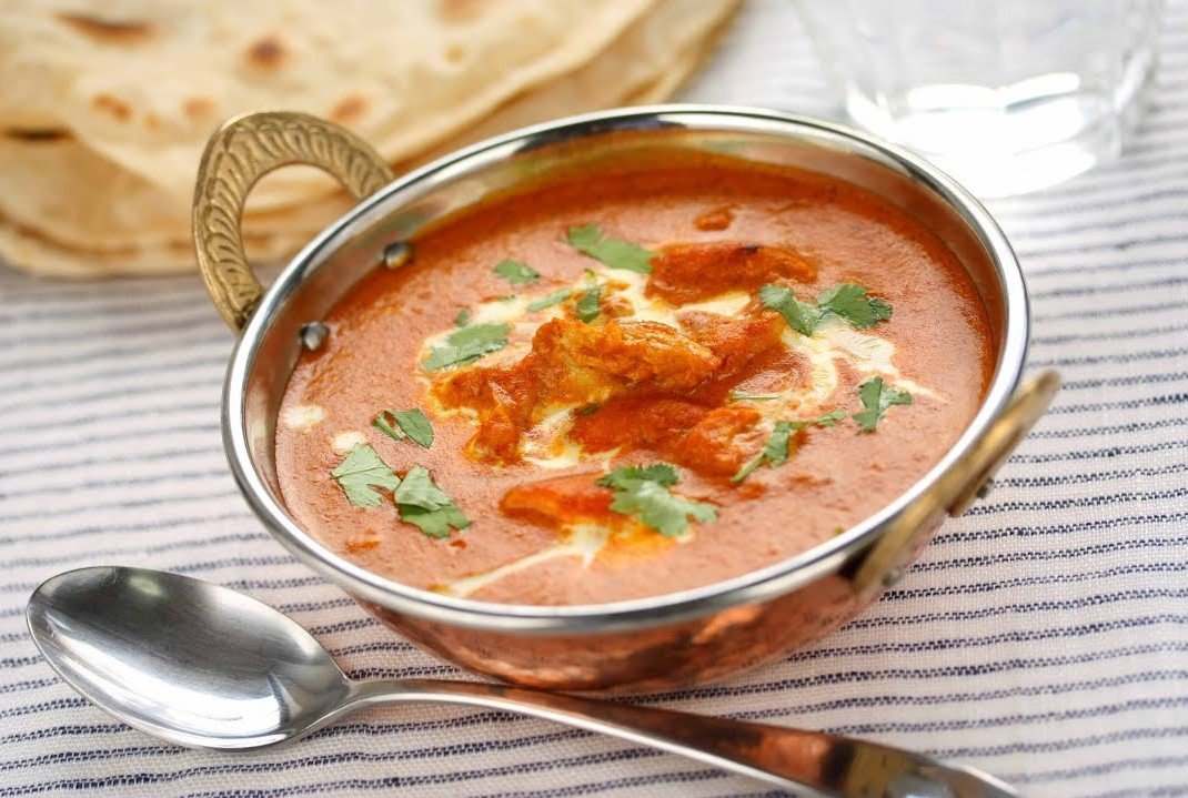 Home-style butter chicken curry in a copper kadai with chapati